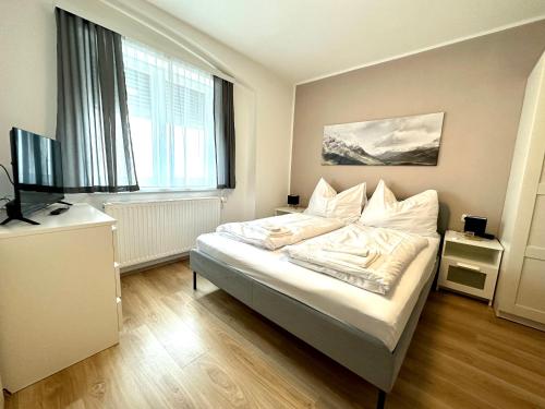 a bedroom with a bed with white sheets and a television at Pension Maier in Villach