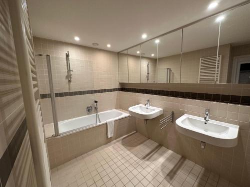 a bathroom with two sinks and a tub and mirrors at 2 Bedroom Apartment in Lovely Louise Area in Brussels