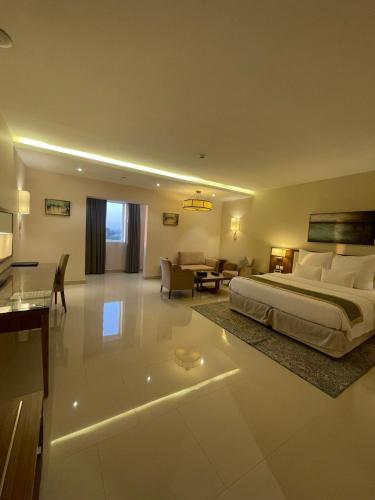 a bedroom with a large bed and a living room at Best Western Plus Buraidah in Buraydah