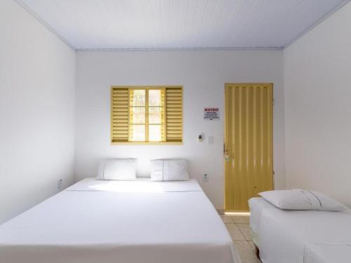 a white room with two beds and a window at Pousada Caldas Novas in Caldas Novas