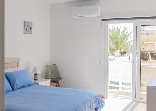 a bedroom with a blue bed and a sliding glass door at Larnaca BeachHouse in Larnaka