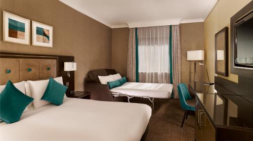 a hotel room with two beds and a chair at DoubleTree by Hilton Woking in Woking