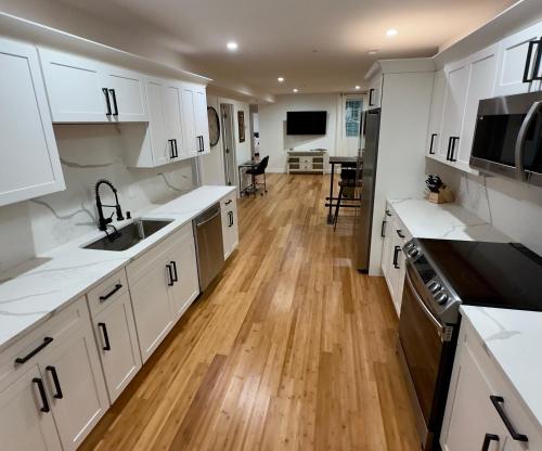 a kitchen with white cabinets and a wooden floor at Perrin Place Unit 1 in Boston
