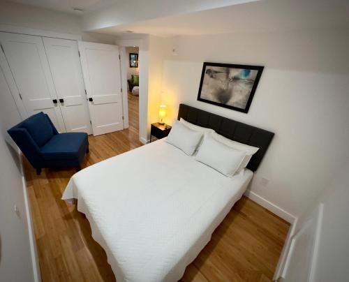 a bedroom with a white bed and a blue chair at Perrin Place Unit 1 in Boston