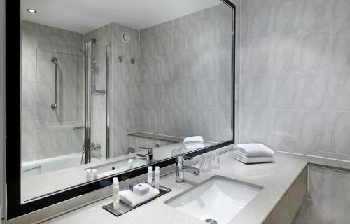 een badkamer met een wastafel, een douche en een bad bij DoubleTree by Hilton Woking in Woking