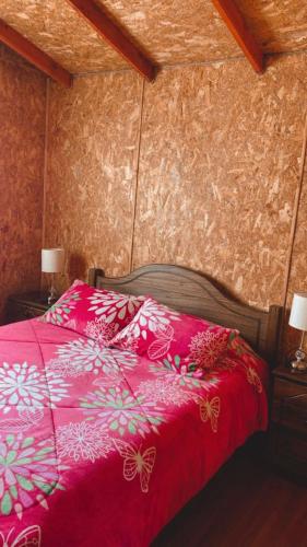 um quarto com uma cama com um edredão rosa em Ebenzer Comidas y Cabañas em Cochrane