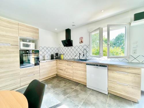 - une cuisine avec des placards en bois et un lave-vaisselle blanc dans l'établissement 2 Maisons - Le Tranquille - Jardin - Terrasse - BBQ, au Mans