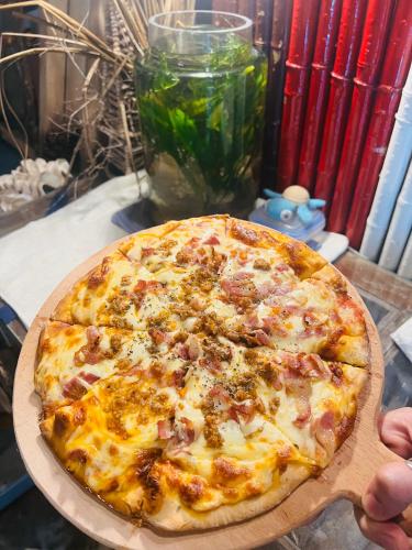 a pizza on a wooden plate on a table at Uyen's House in Con Dao