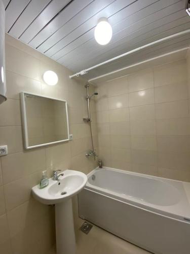 a bathroom with a sink and a tub and a mirror at Apartment in Skopje in Skopje