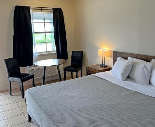 a bedroom with a bed and a table and a window at Red Carpet Inn - Houma in Houma