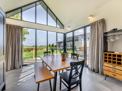 a dining room with a table and chairs and large windows at Shearwater Lodge in Bamburgh