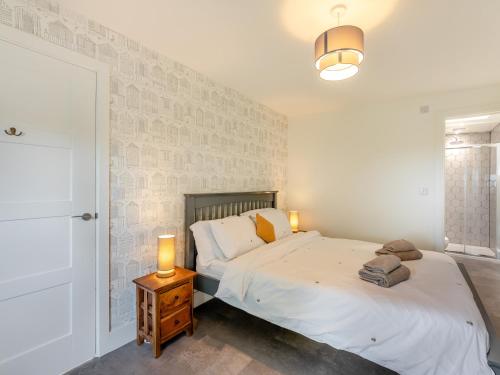 a bedroom with a bed and a table with a lamp at Shearwater Lodge in Bamburgh
