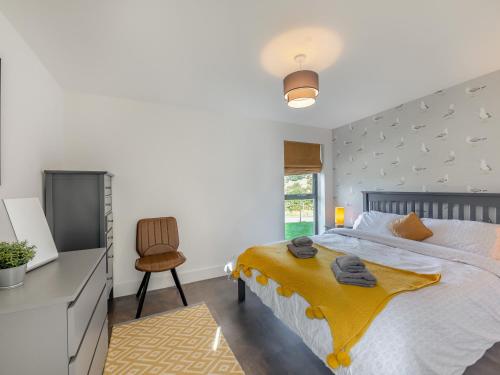 a bedroom with a bed with a yellow blanket on it at Shearwater Lodge in Bamburgh