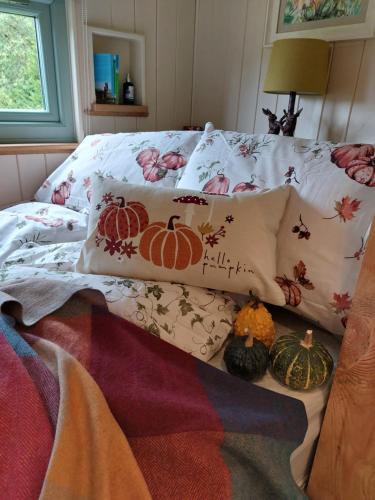 a bed with pillows and pumpkins on it at Secret Garden Shepherd Hut in Macclesfield