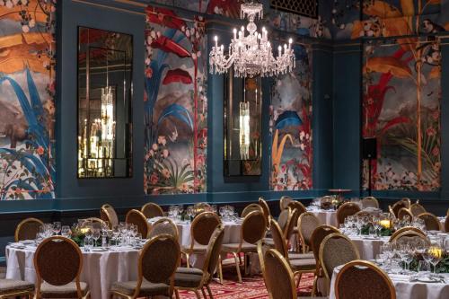 a dining room with tables and chairs and a chandelier at The Bloomsbury Hotel in London