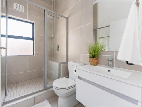 a bathroom with a toilet and a sink and a shower at Ballito Village Luxury Apartments by DropInn in Ballito