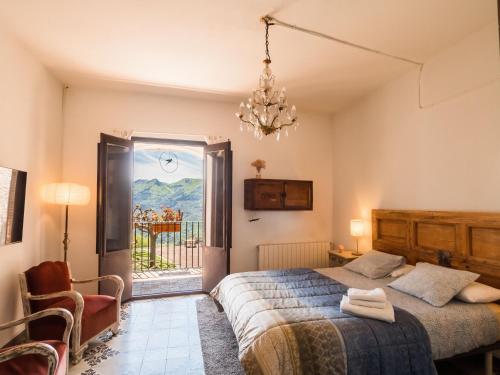 a bedroom with a bed and a window and a chandelier at Masovería Ca la Maria in Arbúcies