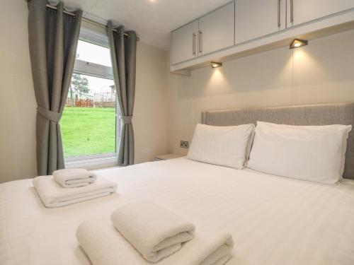 a bedroom with a white bed with towels on it at Meadowsweet Lodge in Carnforth