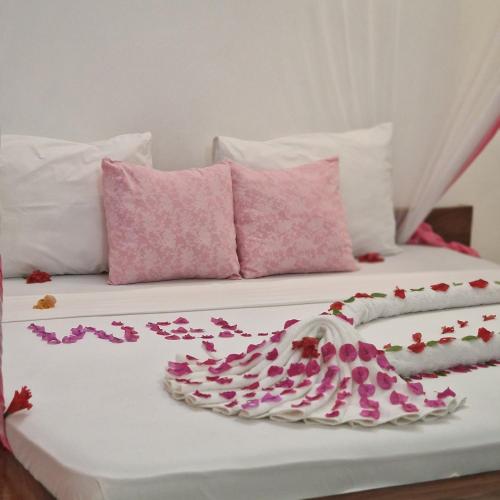 a bed with pink and white pillows and a tray on it at TIANDE Boutique Hotel in Pwani Mchangani