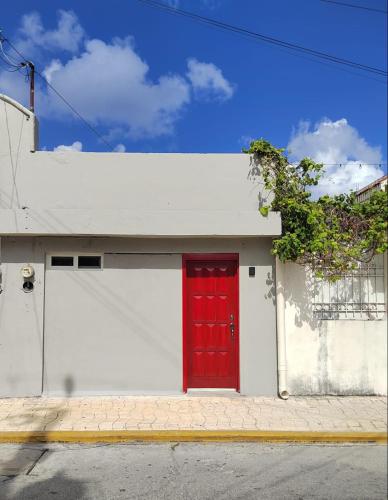una porta rossa sul lato di un edificio bianco di 10th ave Suite a Cozumel
