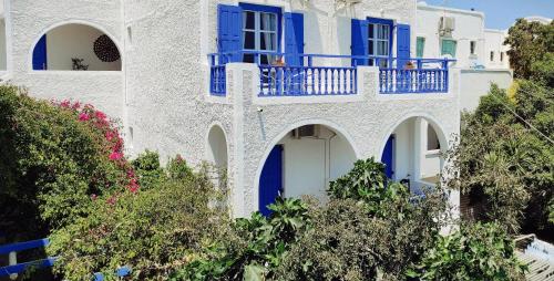 a white house with blue doors and trees at Villa Dioni in Kamari