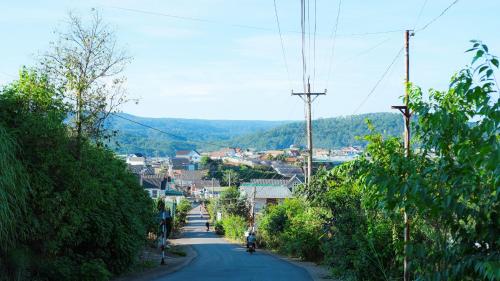 a city street with a person riding a motorcycle down a road at Da Quy Harmony Homestay in Da Lat