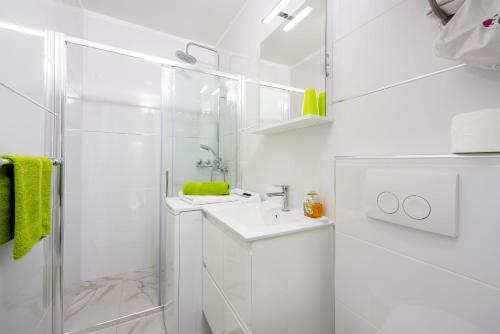 a white bathroom with a shower and a sink at Apartments Lucija in Crikvenica
