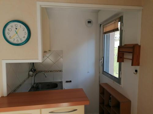 une cuisine avec une horloge murale et un évier dans l'établissement Cauterets centre - Résidence Le marcadau 1, à Cauterets