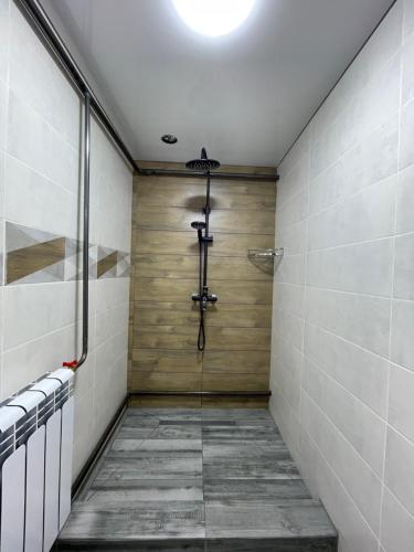 a walk in shower with wooden walls and a glass door at Fam_House in Bishkek