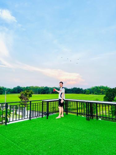 a man standing on a fence in the grass at Farm View Resort @Uthai Thani ฟาร์มวิว รีสอร์ท อุทัยธานี in Nong Khayang