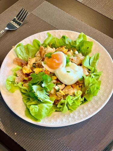 a plate of food with an egg on top of lettuce at Farm View Resort @Uthai Thani ฟาร์มวิว รีสอร์ท อุทัยธานี in Nong Khayang