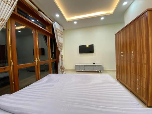 a bedroom with a bed and a tv on a wall at Da Quy Harmony Homestay in Da Lat