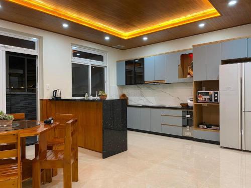 a large kitchen with a table and a refrigerator at Da Quy Harmony Homestay in Da Lat