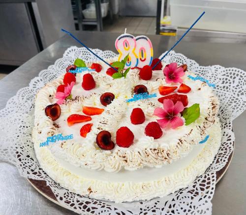 a birthday cake with strawberries and flowers on a table at ALIOS Hôtel Restaurant in Bas-Mauco