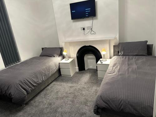 a bedroom with two beds and a tv on the wall at 5-Bed Apartment in Altrincham near airport in Altrincham
