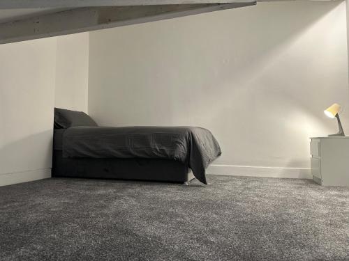 a bedroom with a bed and a white wall at 5-Bed Apartment in Altrincham near airport in Altrincham