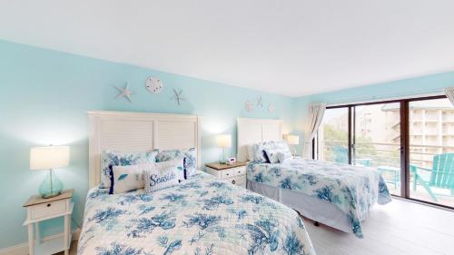 een slaapkamer met twee bedden met blauwe muren en een raam bij 2415 Villamare in Hilton Head Island