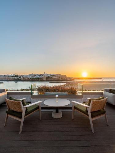a patio with a table and chairs and the sunset at Fairmont La Marina Rabat Sale Hotel in Rabat