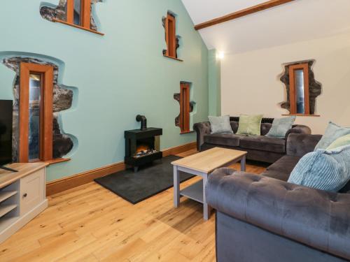 a living room with a couch and a fireplace at The Barn by Lyons in Talybont