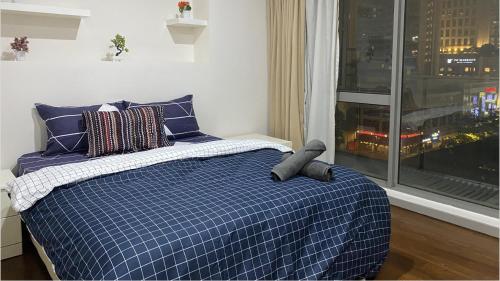 a bedroom with a bed with a blue plaid blanket and a window at Fairlane Residence at Bukit Bintang in Kuala Lumpur