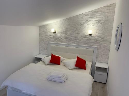 a bedroom with a white bed with red pillows at Vila F&C in Braşov