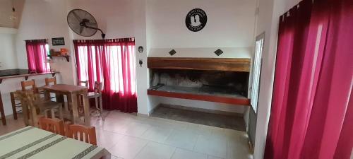 uma sala de estar com lareira e cortinas vermelhas em El Descanso de San José em Sauce Viejo