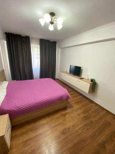 a bedroom with a purple bed and a flat screen tv at Brown Aparts in Chişinău