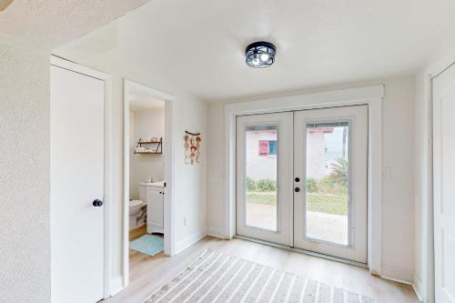 Habitación blanca con puerta y baño en Ocean Beach Bungalow en Ormond Beach