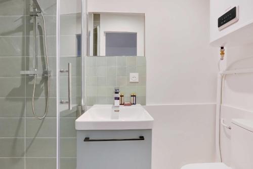 une salle de bain blanche avec un lavabo et une douche dans l'établissement Charming appartement - 1BD-4P - Batignolles, à Paris