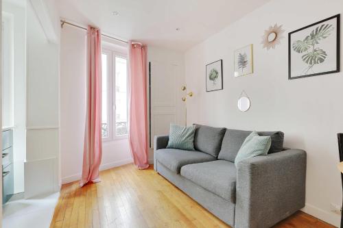 un salon avec un canapé et une fenêtre dans l'établissement Charming appartement - 1BD-4P - Batignolles, à Paris