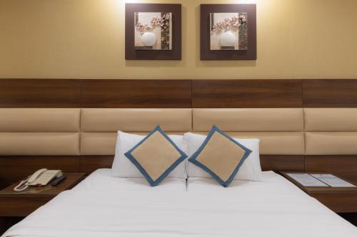 1 dormitorio con 1 cama con 2 almohadas y 2 fotografías en Ehdaa Hotel en La Meca