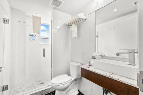a white bathroom with a toilet and a sink at The Fairwind Hotel in Miami Beach