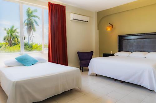 two beds in a room with a window at Caribe Princess in Chetumal