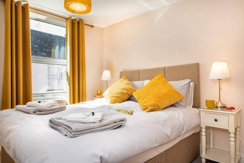 ein Schlafzimmer mit einem Bett mit Handtüchern und einem Fenster in der Unterkunft Cosy Cottage rural village near Tavistock/sleeps 4 in Bere Alston